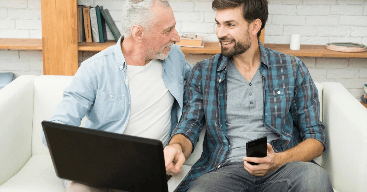Two Happy men sitting on a couch with a laptop