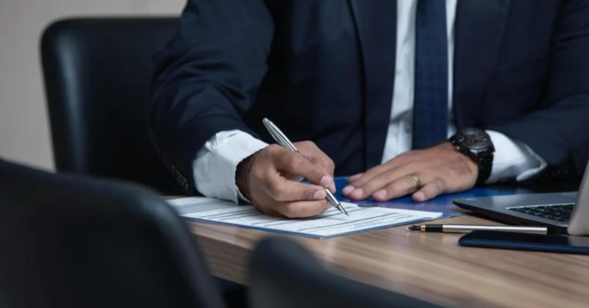 a man writing on paper with pen