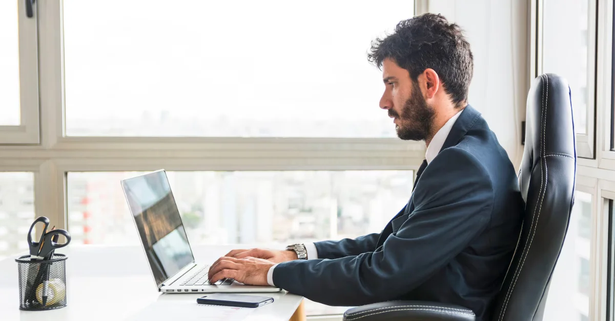 a man typing on his laptop in office