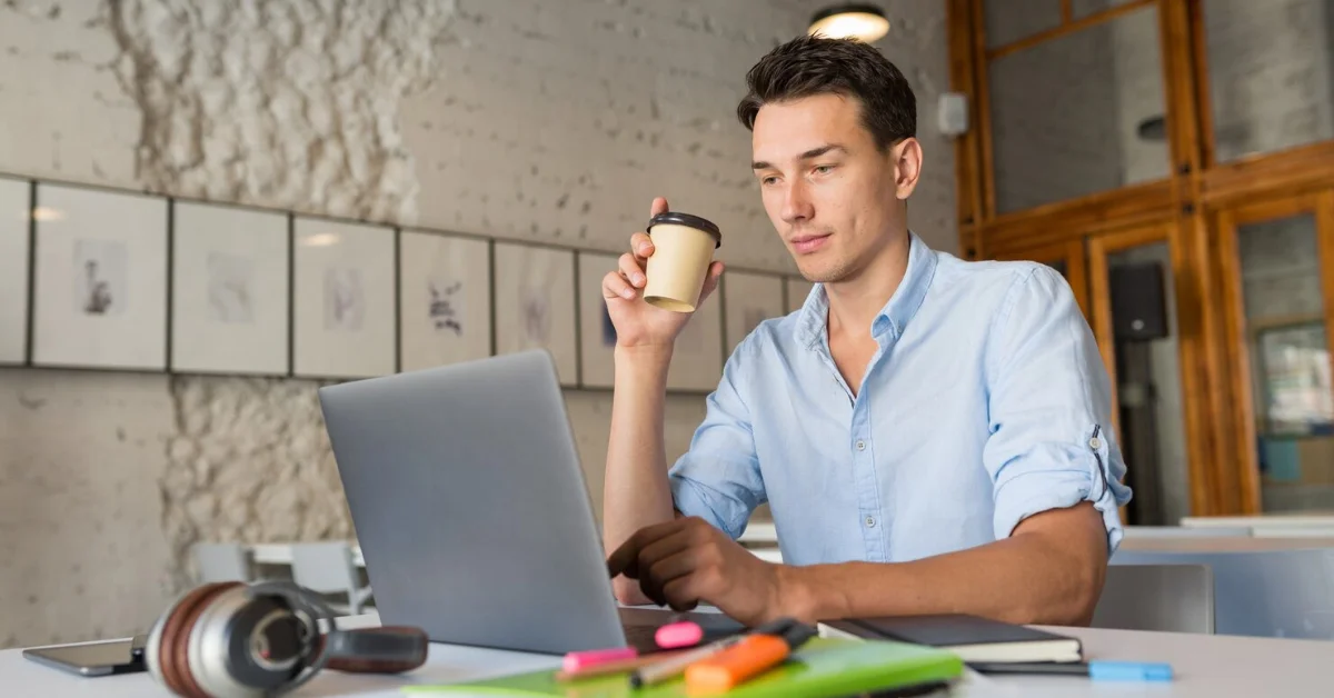a man using laptop while drinking coffee