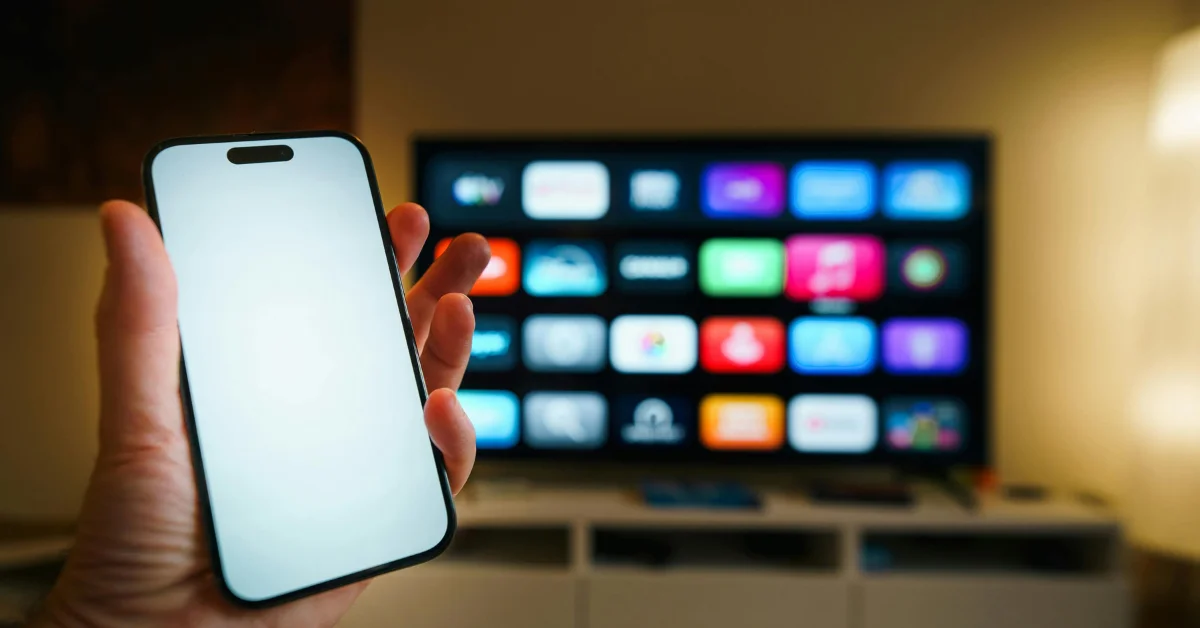 a man showing his phone and tv
