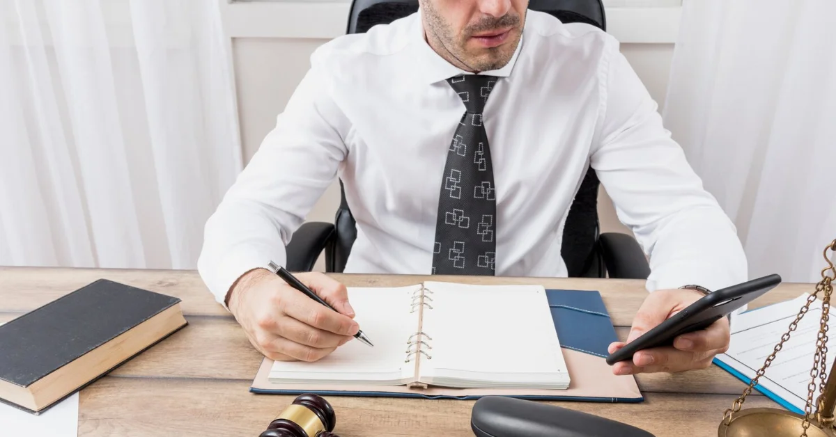 a lawyer writing on paper while using phone